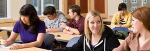 Students sitting at desks in a classroom, some raising hands