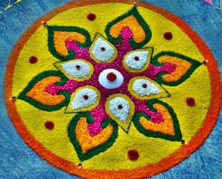 A vibrant square Rangoli pattern featuring symmetrical geometric shapes and contrasting colors.