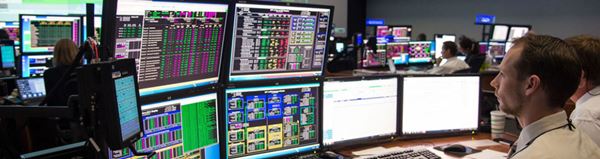Technician monitoring multiple computer screens in a dark control room